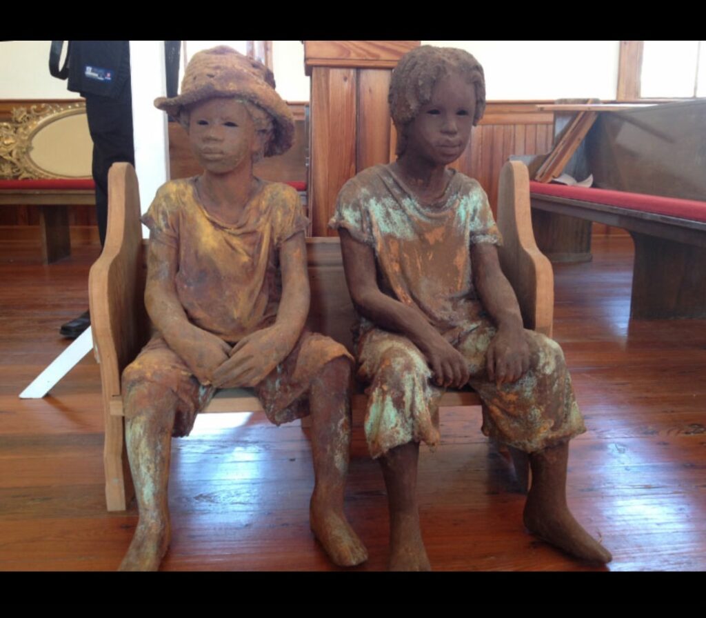 Statue of 2 kids sitting in on a bench at Whitney Plantation